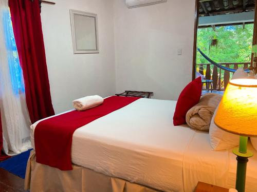 a bedroom with a bed and a lamp and a window at Garden Hotel in Copán Ruinas
