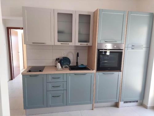 una cucina con elettrodomestici e armadi blu e bianchi di Apartments with a parking space Gradac, Makarska - 21437 a Gradac (Grado)