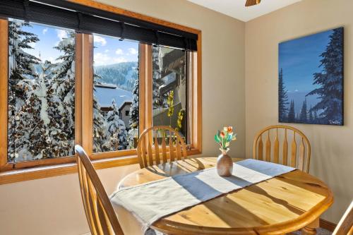 uma sala de jantar com uma mesa e uma grande janela em Snow Creek Village #37 By Bear Country em Sun Peaks