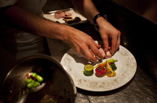 a person preparing a plate of food on a counter at Auberge du Raisin in Cully