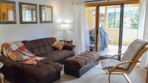 a living room with a brown couch and a chair at Snow Creek Village #49 in Sun Peaks