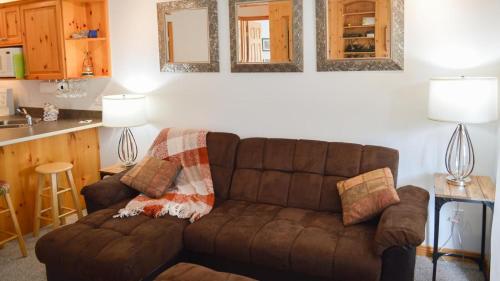 a living room with a brown couch and a kitchen at Snow Creek Village #49 in Sun Peaks