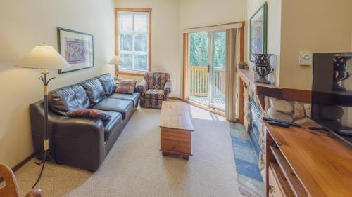 sala de estar con sofá de cuero y TV en Fireside Lodge #419 By Bear Country, en Sun Peaks