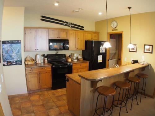 サンピークスにあるCrystal Forest #53 By Bear Countryのキッチン(木製キャビネット付)、カウンター(バースツール付)
