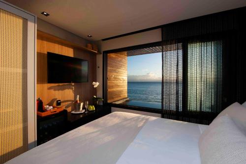 a bedroom with a large bed and a view of the ocean at Pousada Antonella in Morro de São Paulo