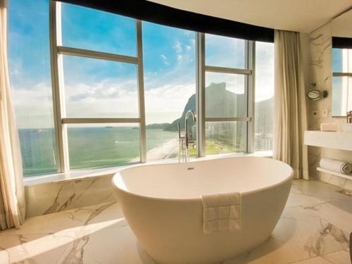 Hotel Nacional Rio de Janeiro في ريو دي جانيرو: حوض استحمام في حمام مع نافذة كبيرة