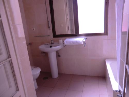 a bathroom with a sink and a toilet and a mirror at Hostal Lima in Valladolid