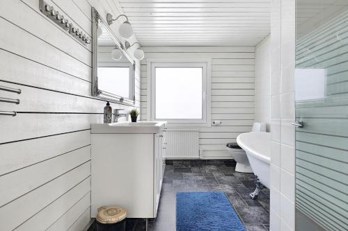 a bathroom with a sink and a toilet and a mirror at Guestly Homes - 3BR Seaside Luxury Villa in Piteå