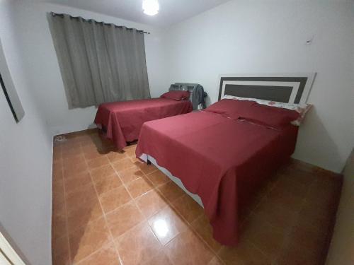 two beds in a room with red sheets at Flat com garagem para até 5 pessoas in Campina Grande