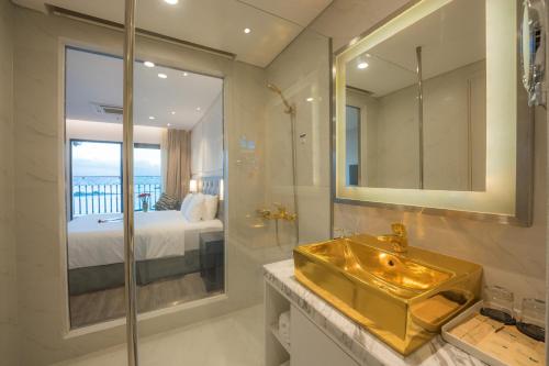a bathroom with a gold sink and a bedroom at Dana Pearl Bay in Danang
