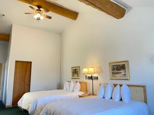 two beds in a room with white walls and a ceiling at Moose Creek Lodge & Suites in Cody