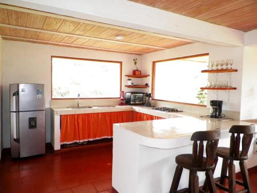 a kitchen with a refrigerator and two windows at Casa Villa Victoria in Villa de Leyva