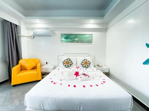 a bedroom with a large white bed with a yellow chair at Bohol Dolphin Bay Resort in Panglao