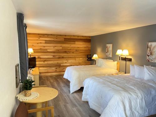 a hotel room with two beds and a wooden wall at Moose Creek Lodge & Suites in Cody