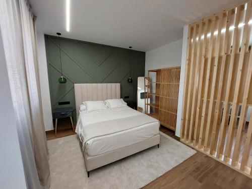 Un dormitorio con una cama blanca y una pared verde. en Apartamento Ricardo, en Carnota