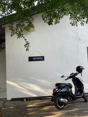 uma moto estacionada em frente a um edifício branco em Hj Hassan Guest House- Studio Unit em Kuala Terengganu