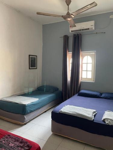 2 camas num quarto com uma ventoinha de tecto em Hj Hassan Guest House Bungalow B em Kuala Terengganu