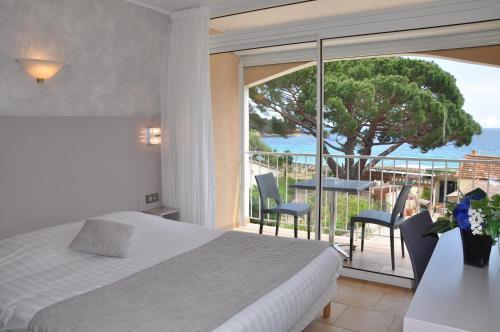 a bedroom with a bed and a view of the ocean at Hotel de la Plage in Le Lavandou