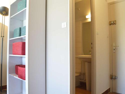 une salle de bain avec un placard à portes blanches et paniers rouges dans l'établissement Studio rénové avec piscine, loggia et parking - 600m de la plage et 200m du port - FR-1-249-357, au Cap d'Agde