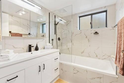 a white bathroom with a sink and a shower at La Costa Vista, Mooloolaba in Mooloolaba