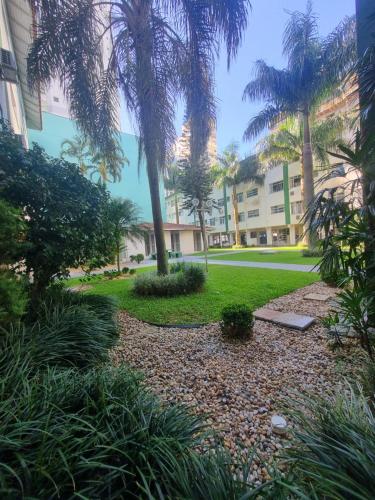 a park with palm trees and a building at Apartamento inteiro 30 metros do mar in Balneário Camboriú