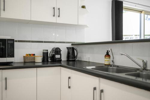 a kitchen with white cabinets and a sink at Beltana - Aldinga Beach - C21 SouthCoast Holidays in Aldinga Beach
