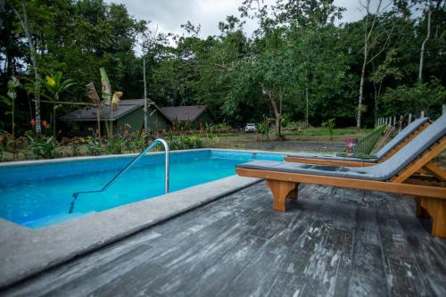 a swimming pool with a wooden bench next to it at Arenal ginger home in Fortuna
