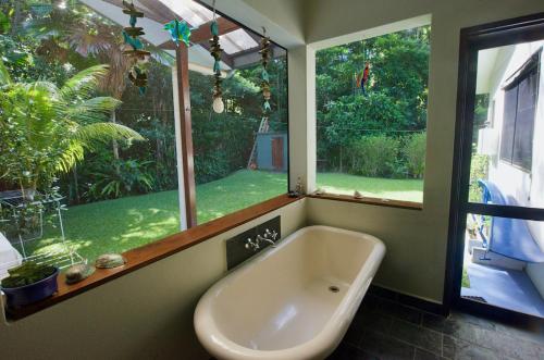 a bath tub in a bathroom with a large window at Thornton Beach Bungalows Daintree in Cape Tribulation