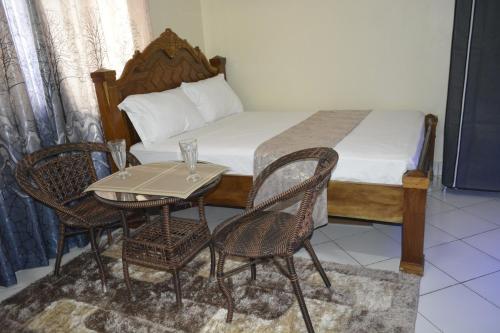 Cette chambre comprend un lit avec une table et des chaises. dans l'établissement Deluxe Studio Apartment - Royal Palms - Mtwapa, à Shimo la Tewa
