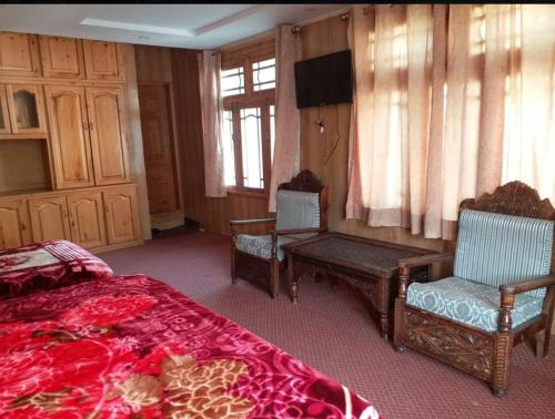 1 dormitorio con 2 sillas, 1 cama y TV en Saspolo chain of G house, en Skardu