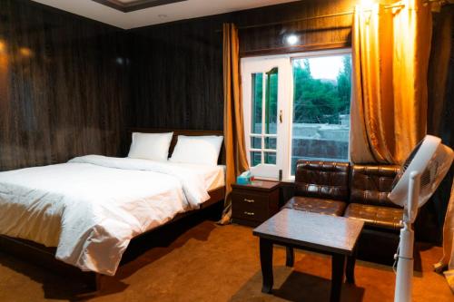 ein Schlafzimmer mit einem Bett, einem Sofa und einem Fenster in der Unterkunft Saspolo chain of G house in Skardu