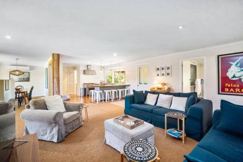 a living room with blue couches and a kitchen at 'The Love Shack' Pet-Friendly Beach Bungalow in Prevelly