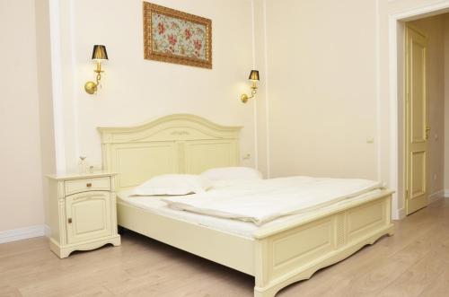 a white bedroom with a bed and a night stand at Hotel Menshikov in Odesa