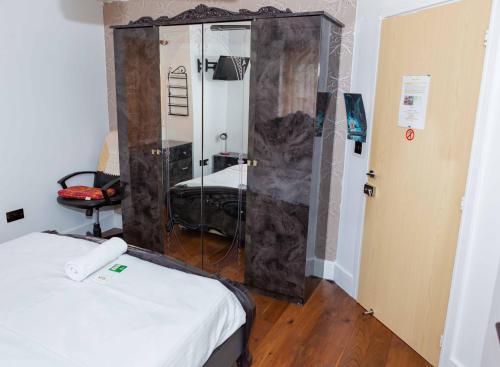 a room with a mirror and a bed in it at Heathrow Garden House - West Drayton, London - Benjamin Guest House in Yiewsley