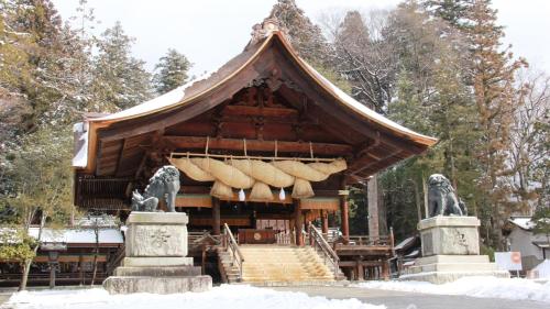 a pavilion with stairs and two statues in the snow at Baigetsu Ryokan in Shimo-suwa