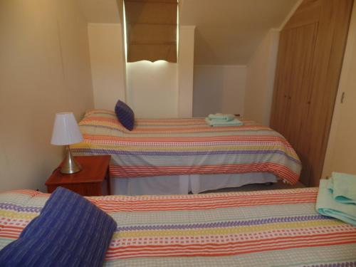 1 dormitorio con 2 camas, lámpara y espejo en Decher Apartment - Puerto Varas, en Puerto Varas