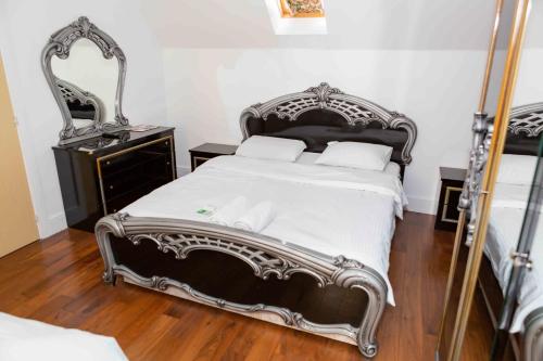 a bedroom with a large bed and a mirror at Heathrow Garden House - West Drayton, London - Benjamin Guest House in Yiewsley