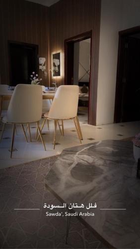 two white chairs and a table in a room at هتان السودة Hattan Al Soudah in Suda