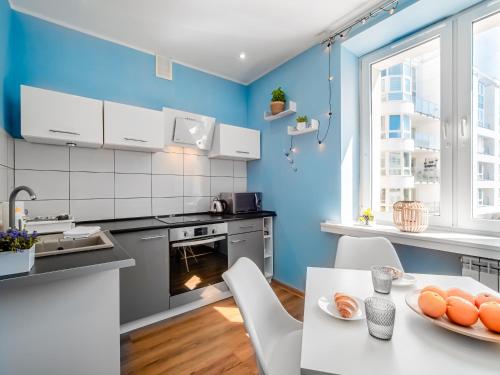 cocina con paredes azules, mesa y sillas en Apartament The Middle One (Train Station - 500m, The Beach - 900 m) en Gdynia