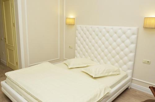 a white bed with two pillows in a room at Hotel Menshikov in Odesa