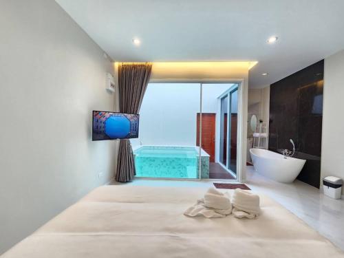 een badkamer met een bad, een wastafel en een televisie bij PVILLA in Ban Phraek Sa