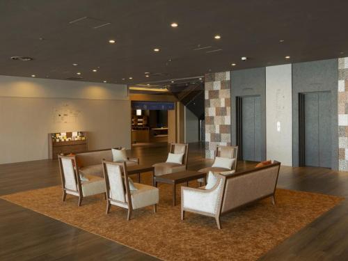 a lobby with chairs and a table and a fireplace at Hotel Sakura Ureshino in Ureshino