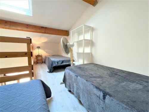 - une chambre avec 2 lits et un ventilateur dans l'établissement Maison avec Mezzanine, 5 Couchages, Piscine, Près Plage - Gruissan - FR-1-229-845, à Gruissan