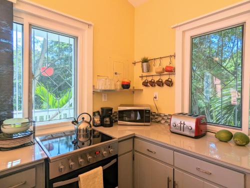 a kitchen with a counter with a microwave and a sink at West Bay Roatan - Sunny & Modern Oasis- 2 Bedrooms - 3 min walk to beach in Roatán