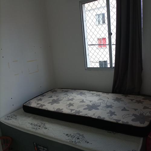 uma cama num quarto com uma janela em Apartamento no vila Olímpia mobiliado em Feira de Santana