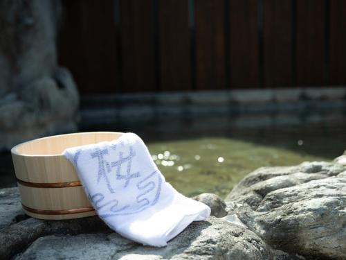 une chaussette assise à côté d'une tasse sur des rochers dans l'établissement Hotel Sakura Ureshino, à Ureshino