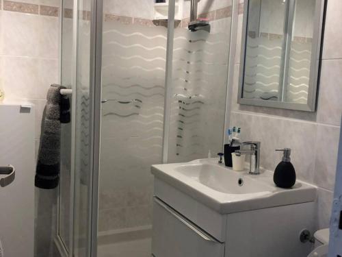 biała łazienka z umywalką i prysznicem w obiekcie Appartement moderne, climatisé, quartier calme, proche commodités, avec parking privatif - FR-1-723-17 w Cap d'Agde