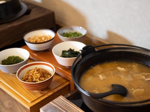 a pot of soup and bowls of food on a table at Hotel Sakura Ureshino in Ureshino