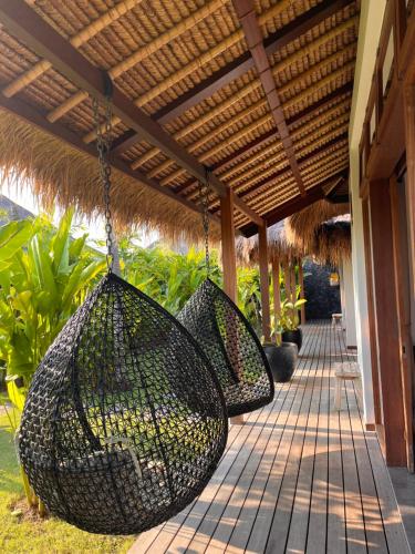 a porch with three baskets hanging from a roof at La Reserva Villas Bali in Jimbaran