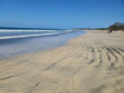 una playa con huellas en la arena y el océano en One Life Villas, en Playa Avellana